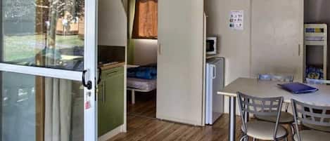 A compact room with a kitchenette, a bed, a table with chairs, and a small refrigerator.