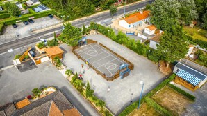 An aerial view of a residential area with a large open space that appears to be a community park or recreational area, surrounded by houses and a road.