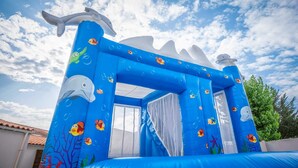 An inflatable play structure with marine-themed designs, including fish and dolphins.