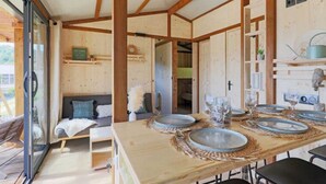 A wooden interior with a dining table set for four, a sofa, and a small kitchen area.