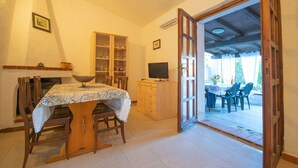 Un comedor con una mesa, sillas, un armario de madera y un televisor.