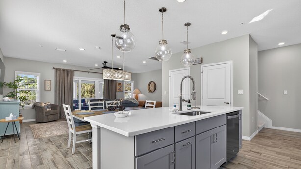 A modern kitchen with a central island, grey cabinets, and pendant lighting. - Desired Lost Key community- walk to beach & golf course + tons of amenities! (Pensacola)