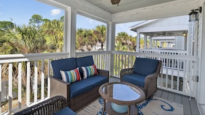 A covered porch with wicker furniture, a ceiling fan, and a view of palm trees. - Desired Lost Key community- walk to beach & golf course + tons of amenities! (Pensacola)