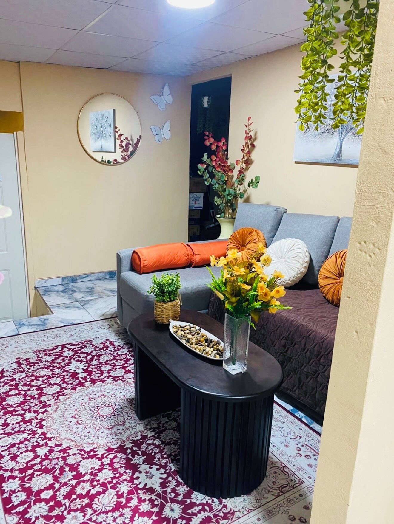 Un salon comprenant un canapé, une table basse agrémentée d’objets décoratifs, un tapis à motifs et des œuvres d’art murales.