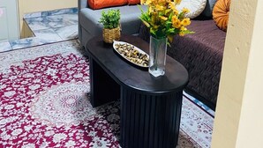A living room with a sofa, a coffee table with decorative items, a patterned rug, and wall art.