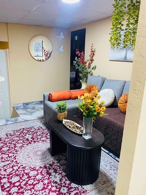 A living room with a sofa, a coffee table with decorative items, a patterned rug, and wall art.