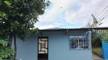 A small, single-story building with a blue exterior, a window with decorative metal bars, and a satellite dish on the roof.