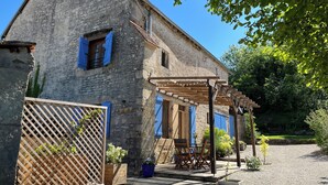 A stone building with blue shutters, a wooden pergola, and outdoor seating. - Charming country house with a Scandinavian bath outside. Dogs welcome! (Magny-Lambert)