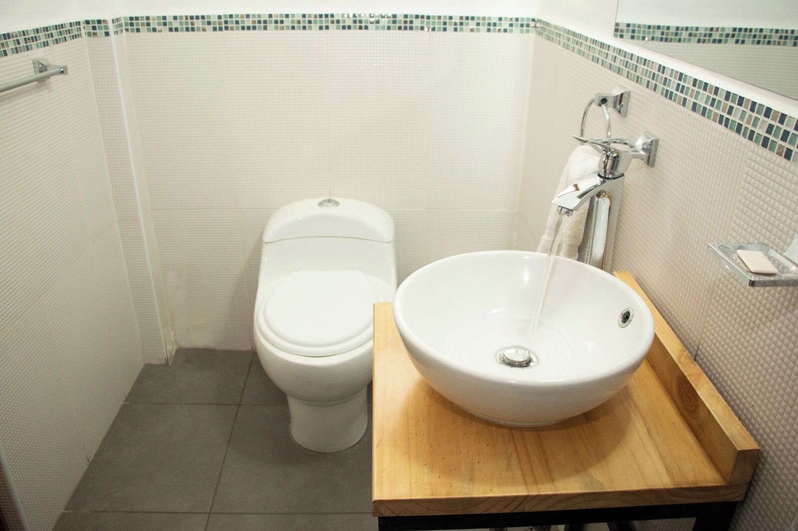 A bathroom with a toilet, a sink, and a mirror.
