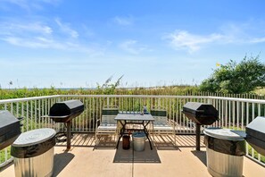 Ein Balkon mit Tisch, zwei Stühlen und zwei Grillanlagen.
