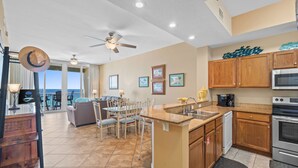 A spacious kitchen with wooden cabinets, a central island, and a dining area with a view. - Gorgeous “Dolphin Delight” 616, Penthouse, Free Activities Included! (Fort Walton Beach)