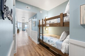 Ein Schlafzimmer mit Etagenbetten, einem Holzkopfteil, einer Wandleuchte und einem gerahmten Bild.