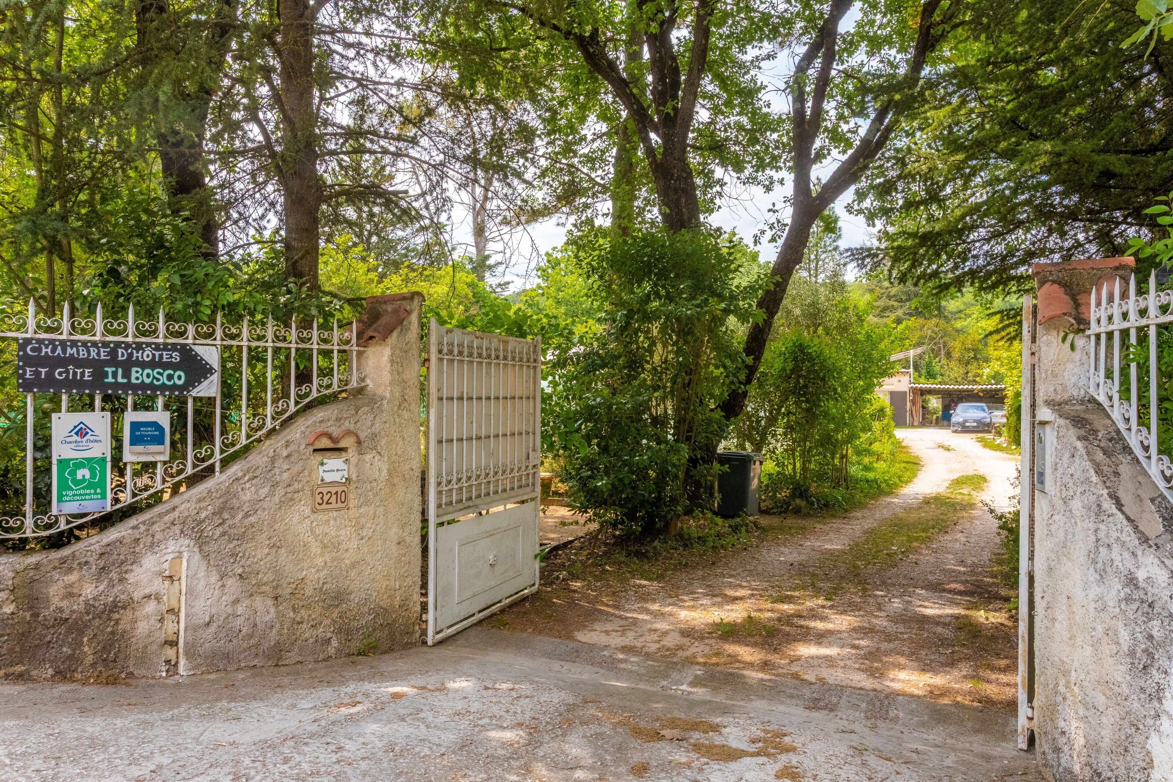 Un cancello con un cartello che indica 'CHAMBRE D'HOTES ET CITE IL BOSCO' e una cassetta delle lettere con il numero '3210'.