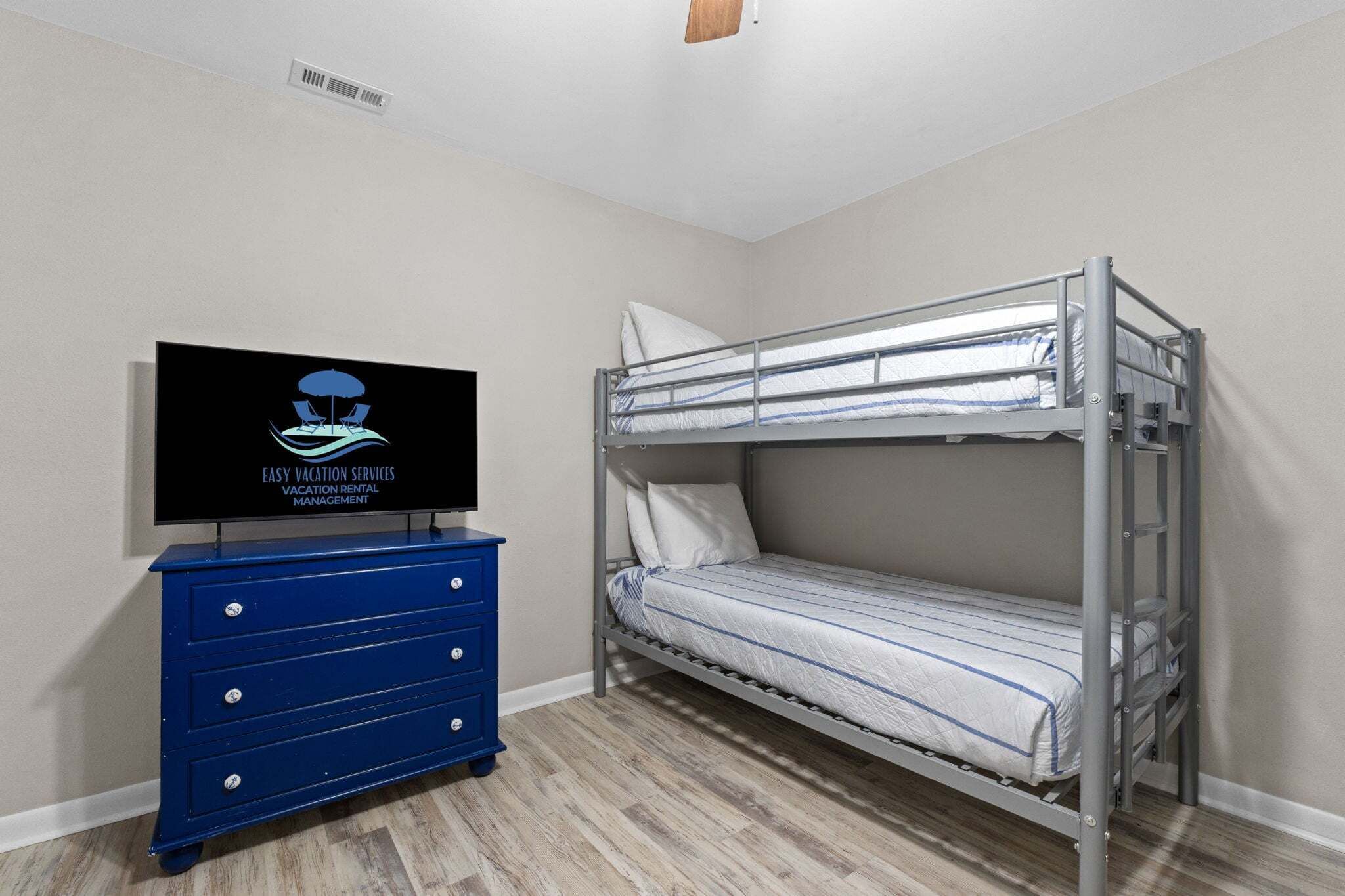 Een stapelbed met een televisie op een dressoir in een kamer met houten vloeren.