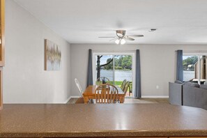 Eine moderne Küche mit Essbereich, Deckenventilator und Seeblick durch große Fenster.