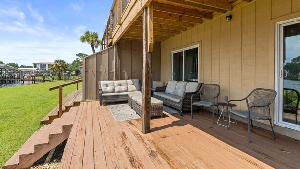 Een overdekt terras met houten vloer, een bank en stoelen.