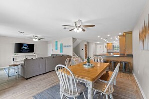 A modern living room with a sofa, dining table, chairs, and ceiling fans. - Panhandle Paradise, Waterfront, 2 Dog Friendly in Fort Walton Beach. Free Activities Included! (Fort Walton Beach)