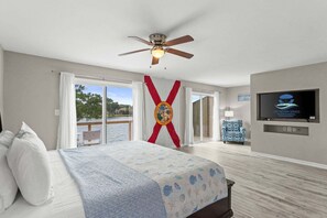 A hotel room with a bed, a ceiling fan, a TV, and a view of the outdoors. - Panhandle Paradise, Waterfront, 2 Dog Friendly in Fort Walton Beach. Free Activities Included! (Fort Walton Beach)