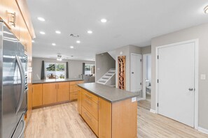 A modern kitchen with wooden cabinets, a stainless steel refrigerator, and a built-in island. - Panhandle Paradise, Waterfront, 2 Dog Friendly in Fort Walton Beach. Free Activities Included! (Fort Walton Beach)