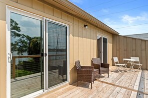 A covered outdoor deck with sliding glass doors, wicker furniture, and a view of the surrounding area. - Panhandle Paradise, Waterfront, 2 Dog Friendly in Fort Walton Beach. Free Activities Included! (Fort Walton Beach)
