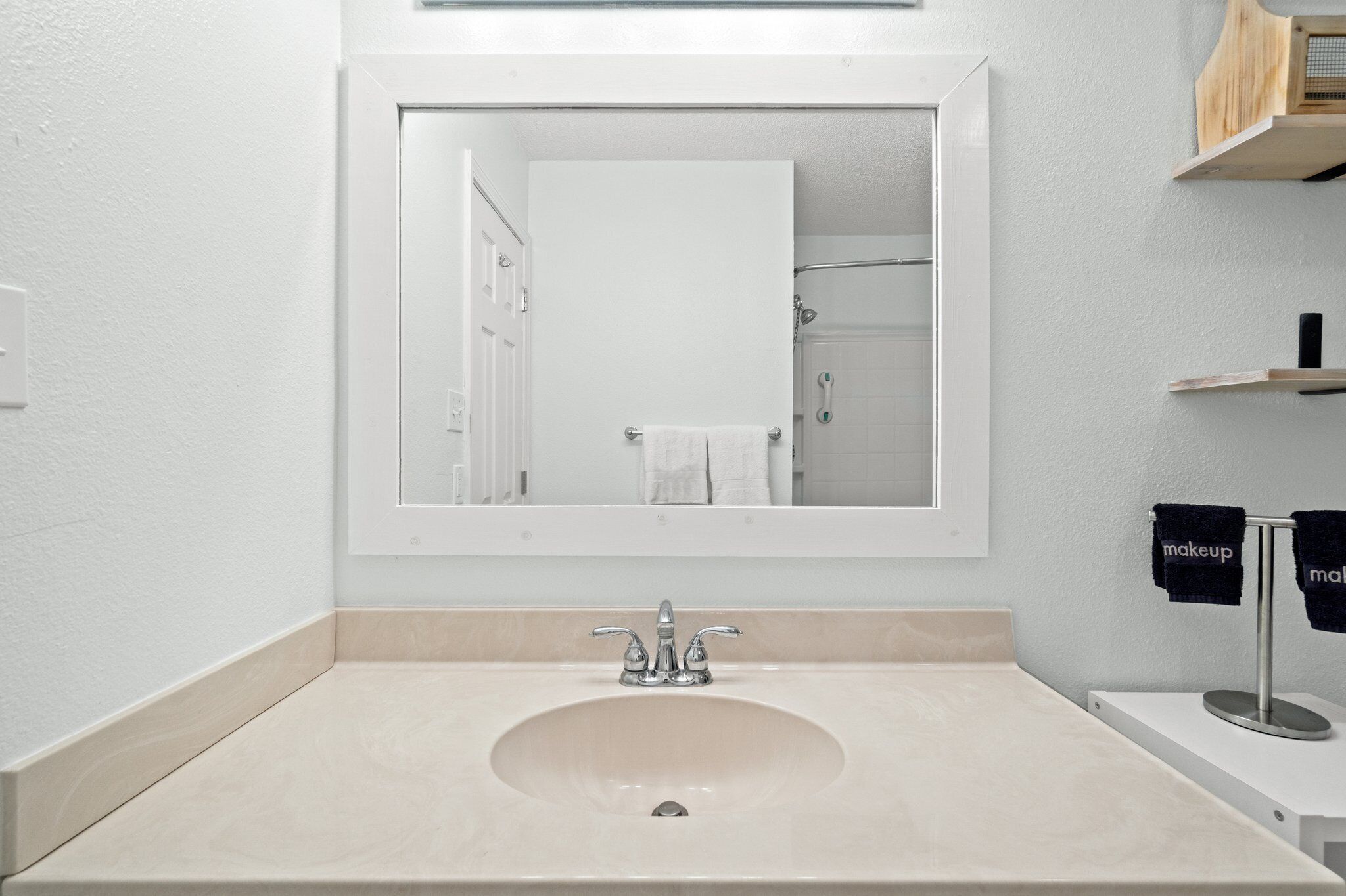 A bathroom with a large mirror, a sink, and a towel rack with towels.