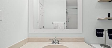 A bathroom with a large mirror, a sink, and a towel rack with towels.