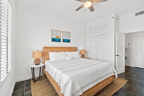 Ein Schlafzimmer mit einem Bett, zwei Wandlampen, einem Deckenventilator und zwei gerahmten Bildern an der Wand.