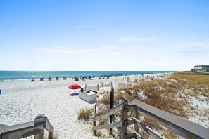 A beach with a wooden walkway leading to the shore, a row of beach umbrellas, and a sandy beach area. - Beachfront Condo with Pool, Hot Tub & Free Beach Service – Perfect for Families! (Fort Walton Beach)