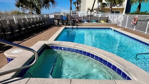 Piscina com borda azulejada, corrimão de metal e cerca branca ao redor.