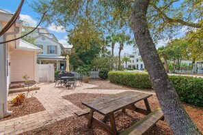 A backyard with a wooden picnic table, a barbecue grill, and a white fence. - ⛱️Walk to Beach | Steps from Neighborhood Pool | Best Nest☀️ (Destin)