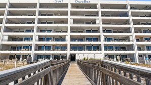 A multi-story hotel with balconies, a wooden walkway, and a beach view. - Beachfront~Beach Service~Stunning Views~Free Activities~Surf Dweller 210 (Fort Walton Beach)
