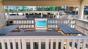 A poolside area with wooden benches and a pool. - Beachfront~Beach Service~Stunning Views~Free Activities~Surf Dweller 210 (Fort Walton Beach)