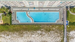Vista aérea de un hotel con una amplia piscina rectangular, varios balcones y una zona de playa.