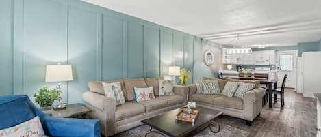 A living room with two sofas, a coffee table, and a dining area with a table and chairs.