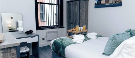 Une chambre d’hôtel moderne, équipée d’un lit, d’un bureau, d’une armoire, d’une fenêtre avec des stores et d’un tableau au mur.