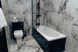 Un baño con inodoro, bidé y bañera, todo con suelo y paredes de mármol.