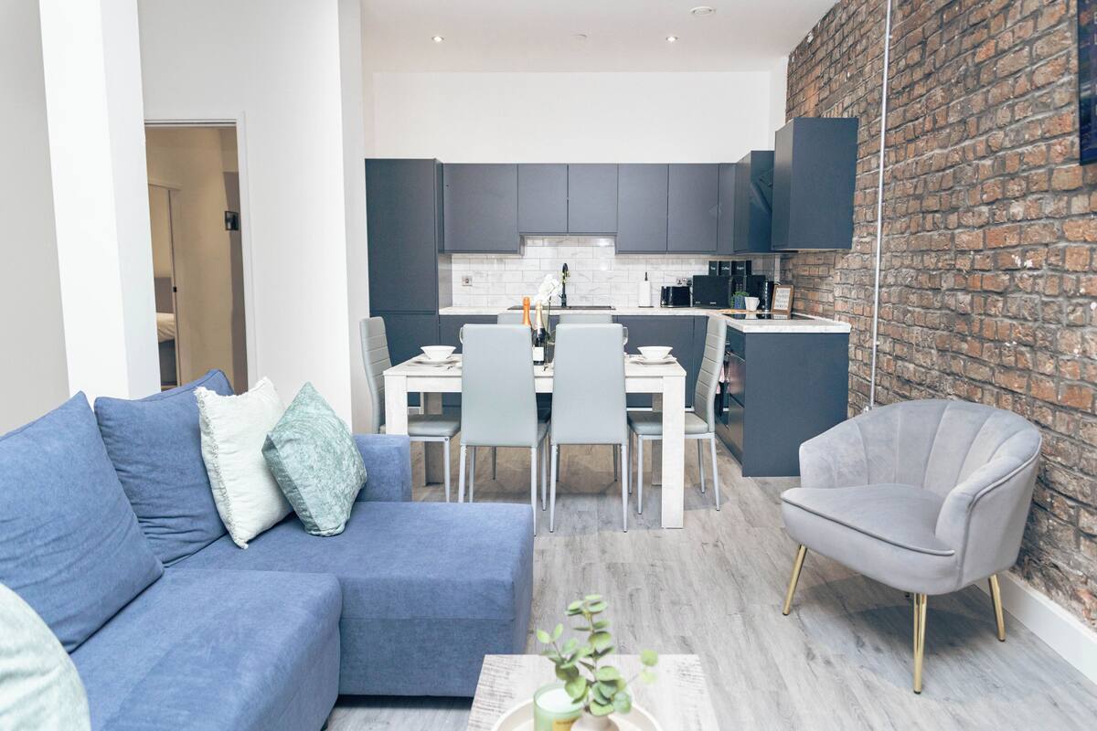 A modern living room with a sofa, armchairs, and a dining area with a table and chairs.