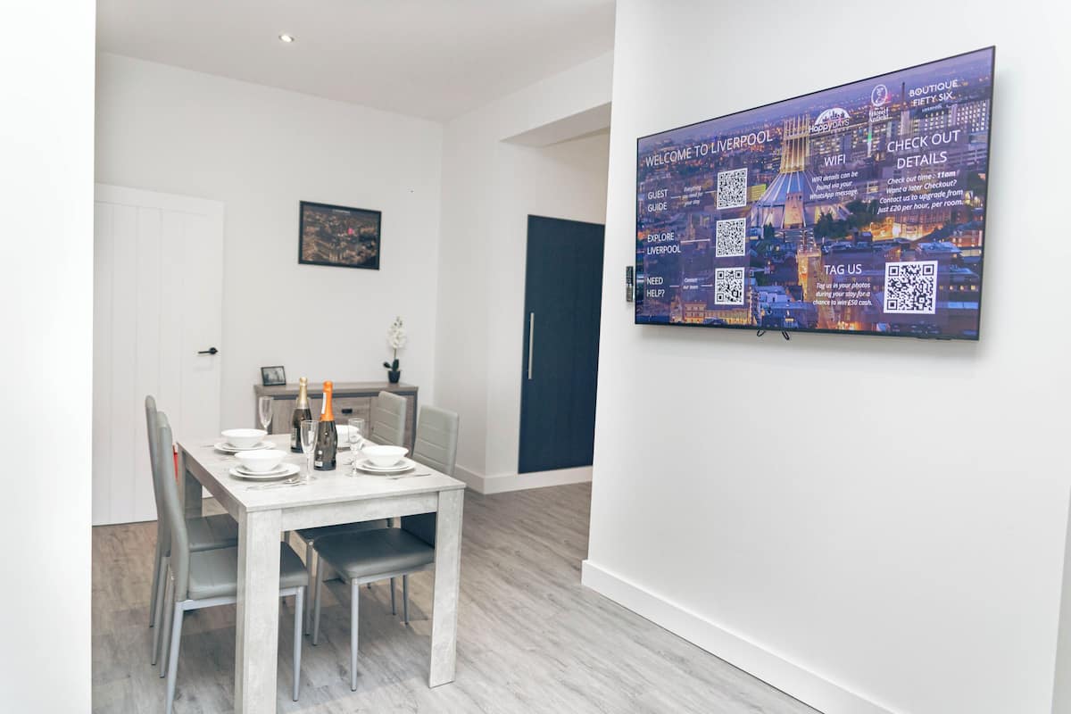 A modern dining area with a white table set for four, a framed picture on the wall, and a large cityscape poster.