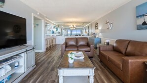 Una sala de estar moderna con un sofá de cuero marrón, una mesa de centro de madera y un televisor de pantalla plana.