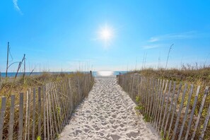 A sandy beach path flanked by wooden fences leading to the sea under a clear sky. - Moondrifter 205 (Panama City Beach)