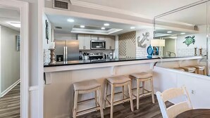 Una cocina moderna con una isla central, taburetes de bar y un espejo grande.