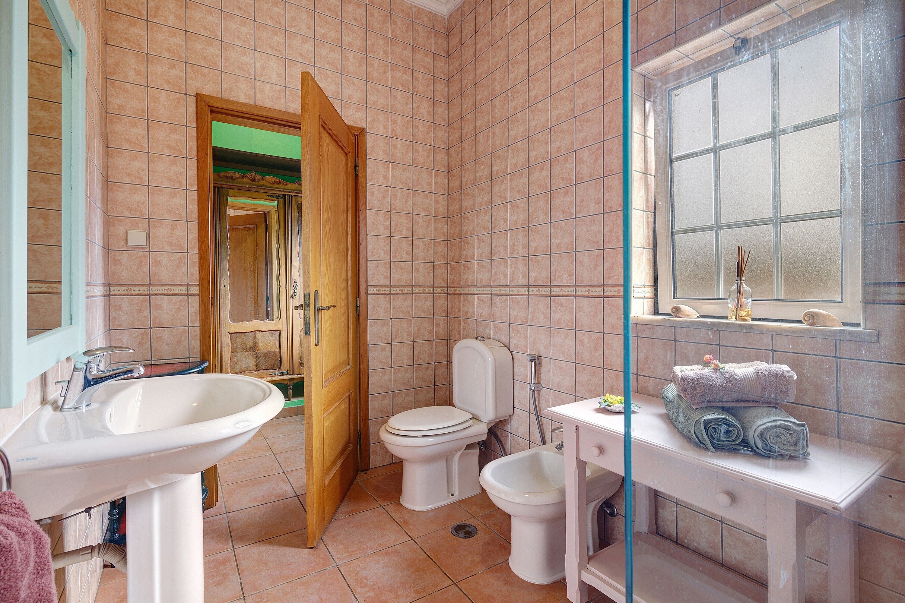 Ein Badezimmer mit Waschbecken, Toilette und Bidet, einem Spiegel und einem Fenster mit Blick.