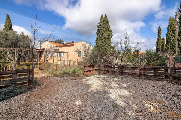 A gravel driveway, wooden fences, and a building with a tiled roof.