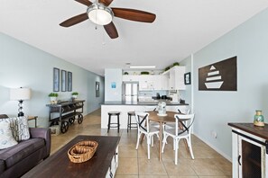 Ein modernes Wohnzimmer mit einem dunkelbraunen Sofa, einem Holztisch und einem Deckenventilator.