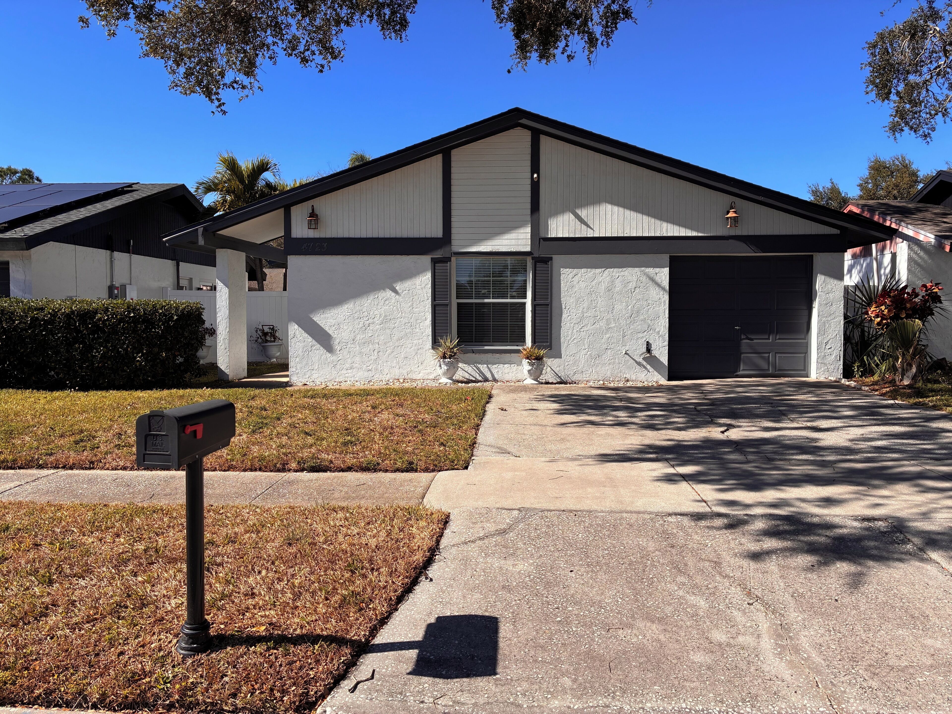 A residential house with a white exterior, a garage, and a front yard with a mailbox.