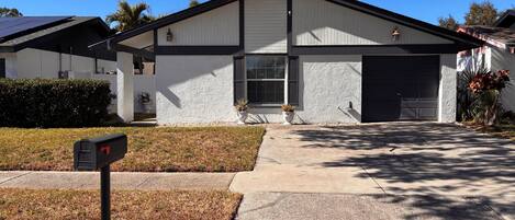 A residential house with a white exterior, a garage, and a front yard with a mailbox.