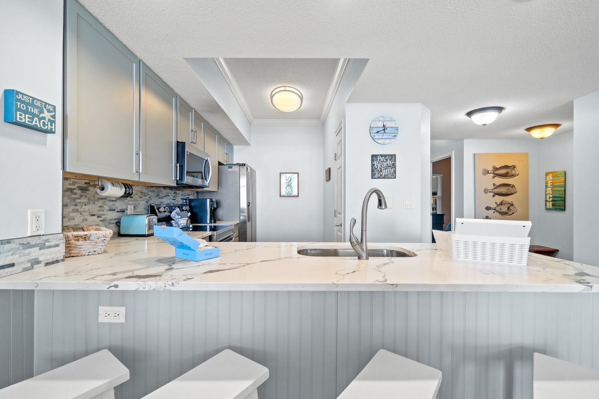 A modern kitchen with a marble countertop, stainless steel appliances, and a built-in sink.