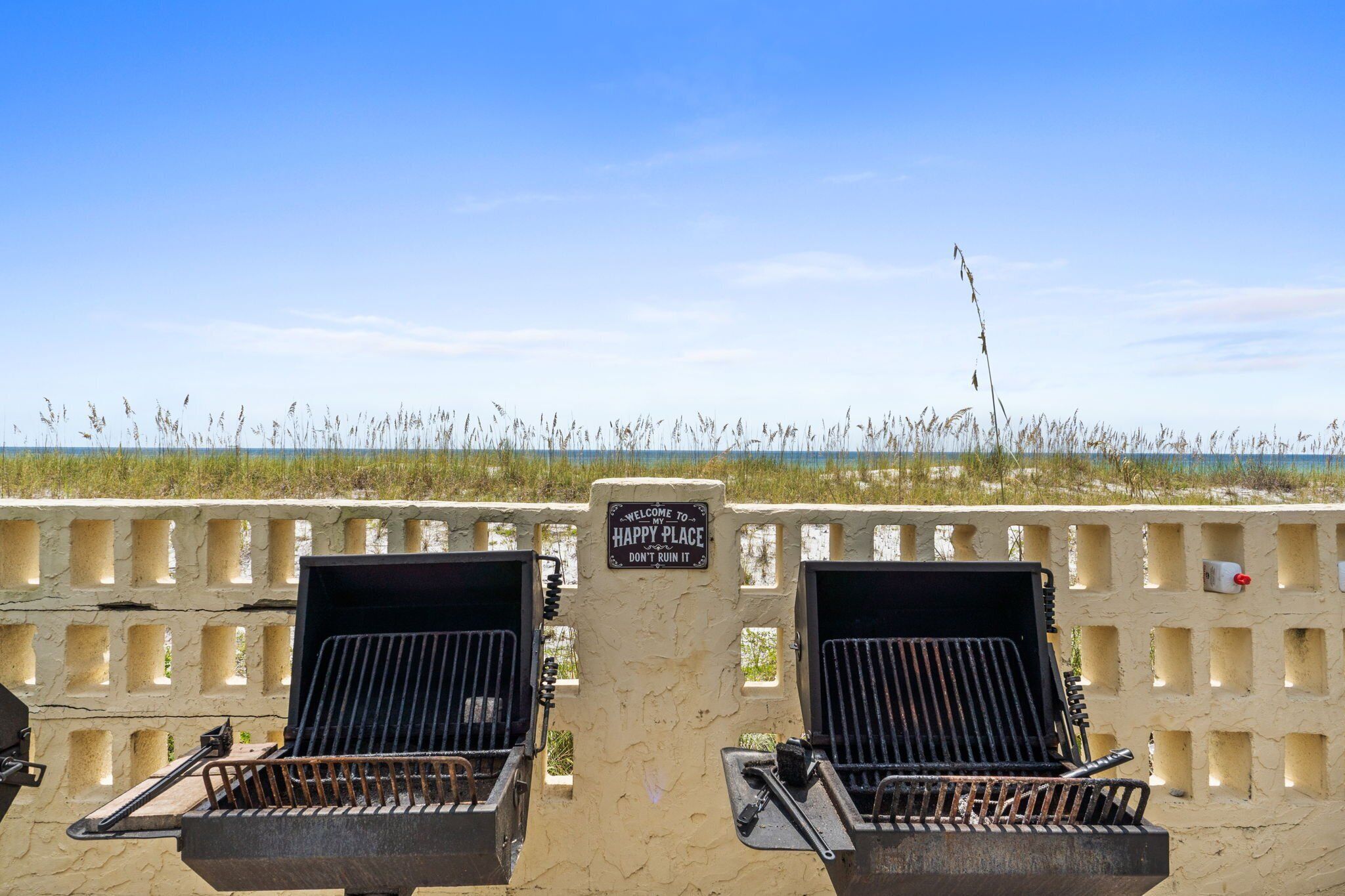 Een grillplaats aan het strand, met een bord waarop staat: "Welkom bij Happy Place, verpest het niet."