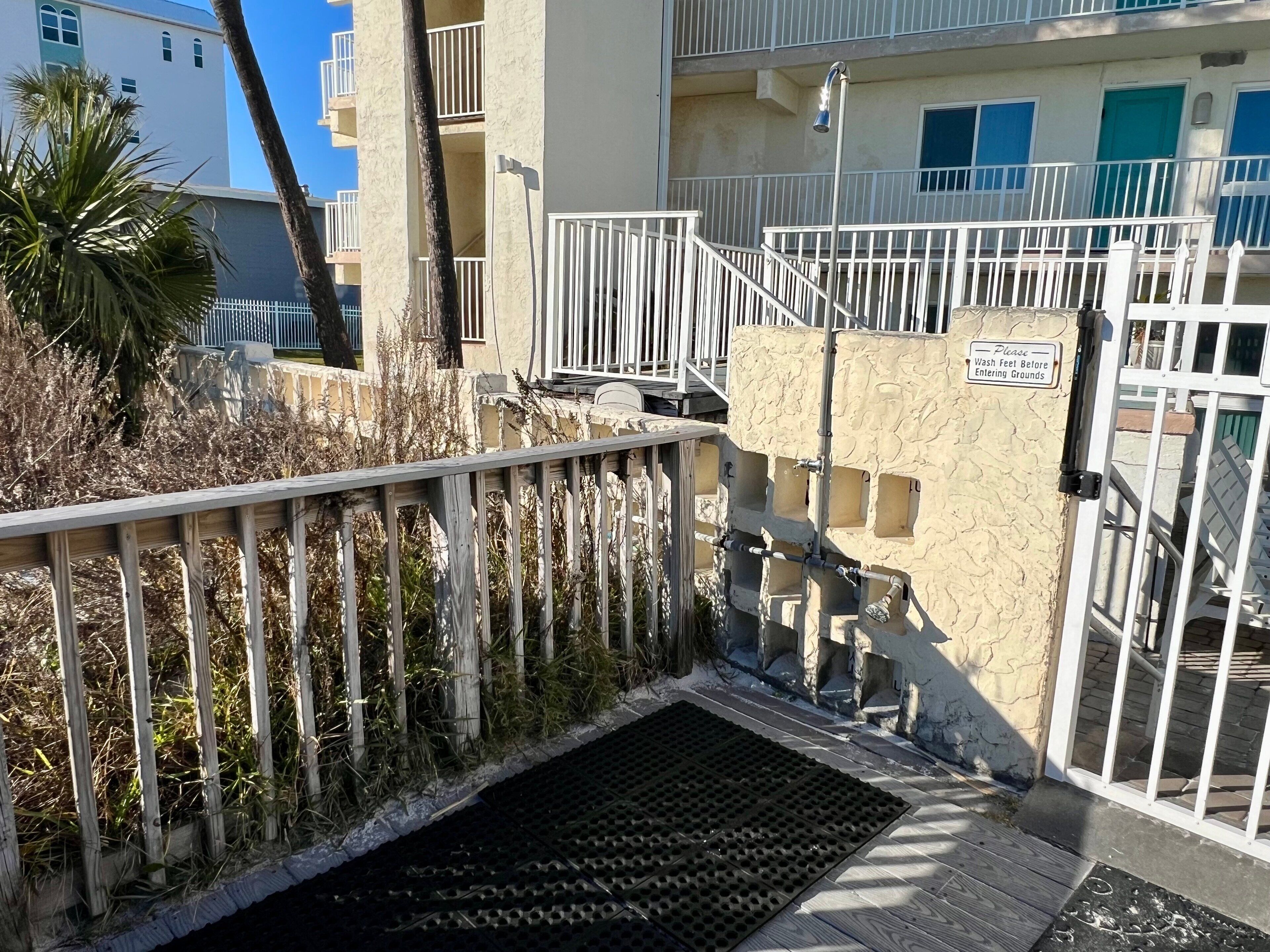 A gated entrance with a metal staircase leading to a building with balconies.