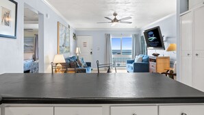 Une chambre d’hôtel avec vue sur l’océan, un ventilateur de plafond, une télévision et un coin repas avec une table et des chaises.